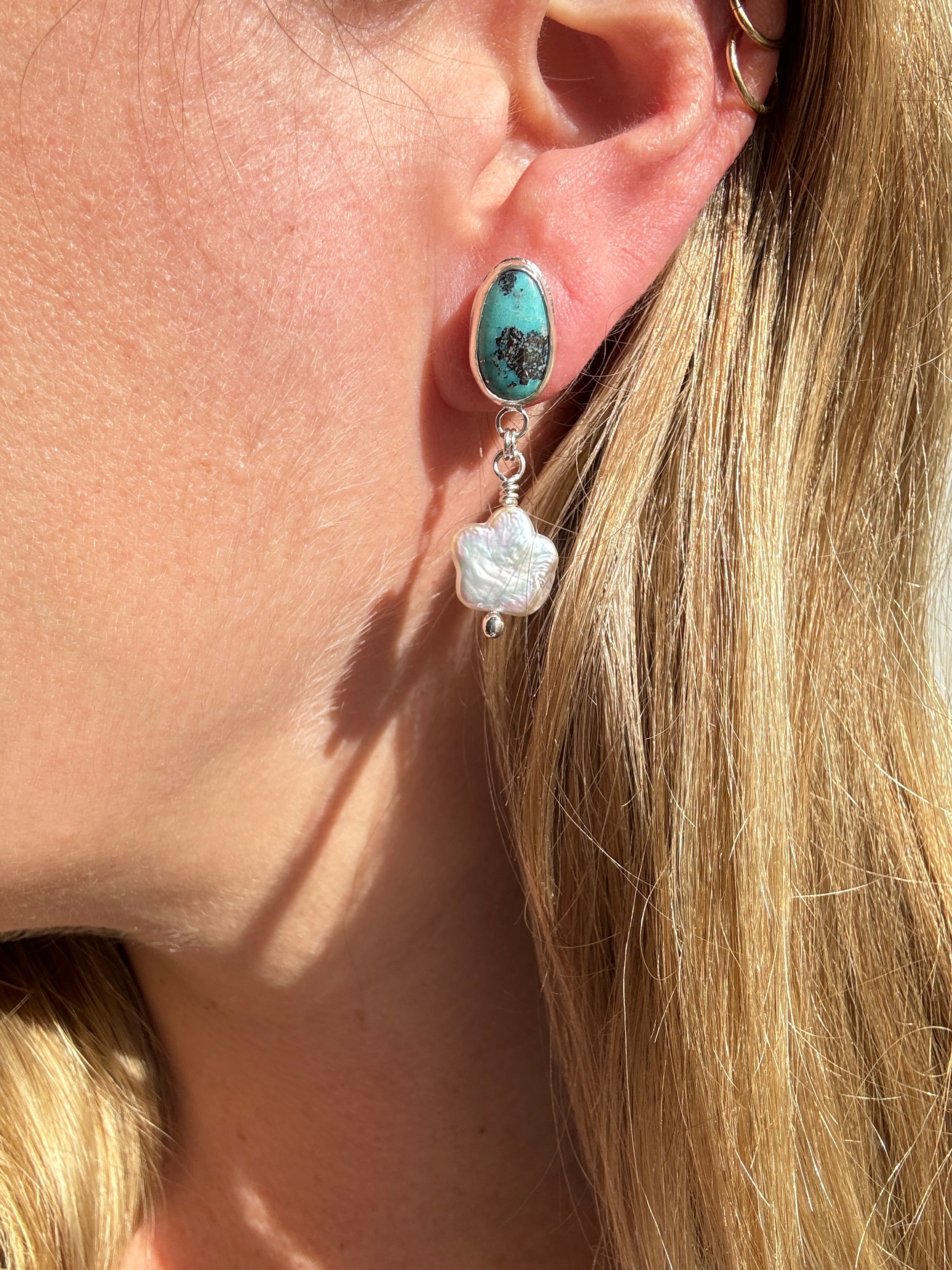 Robin's Egg Blue Kingman Turquoise set in a fine silver bezel with flower shaped pearls dangling below. The posts and ear backs are sterling silver.&nbsp;