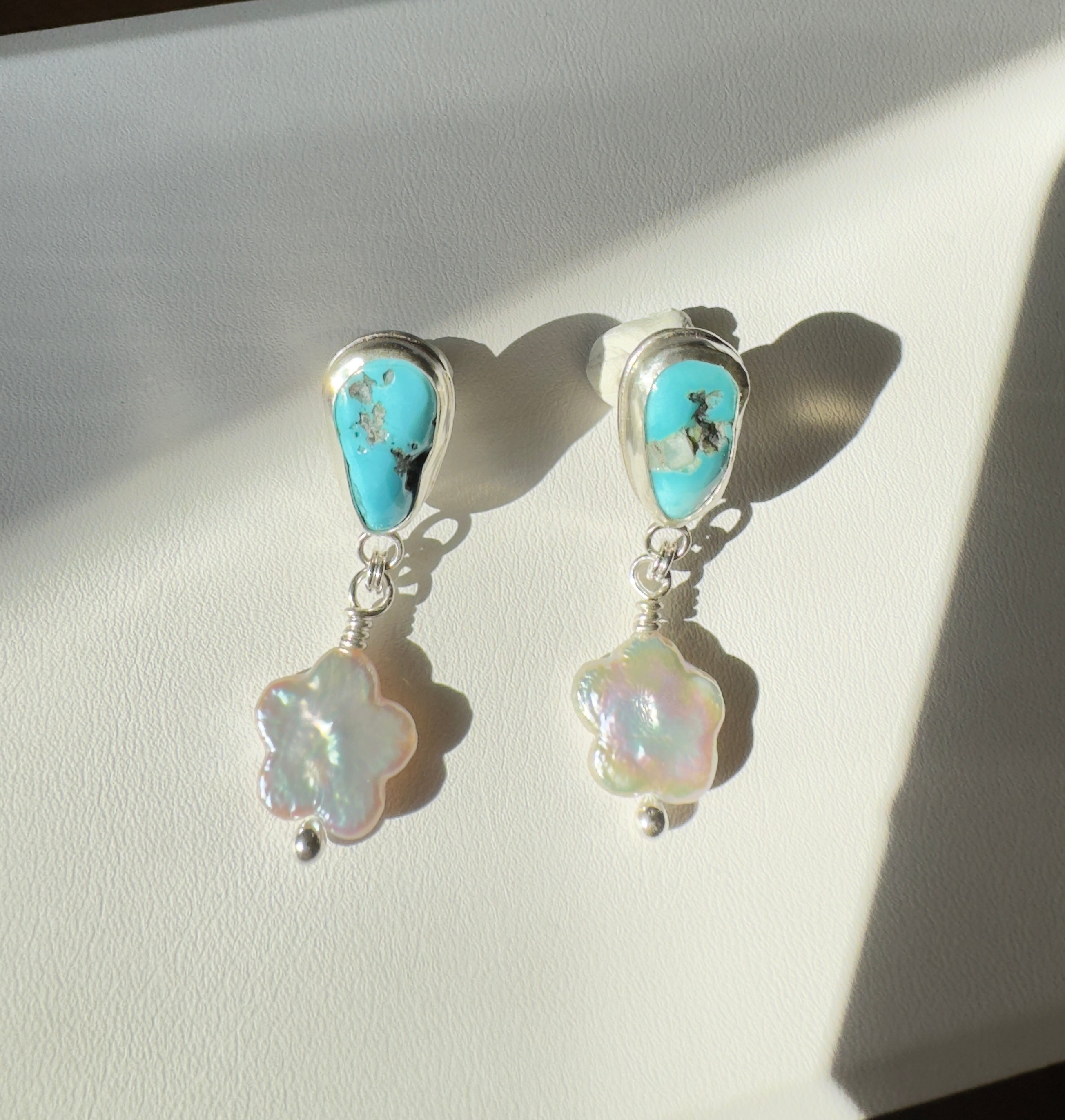 Castle Dome Turquoise set in a fine silver bezel with flower shaped pearls dangling below. The posts and ear backs are sterling silver.