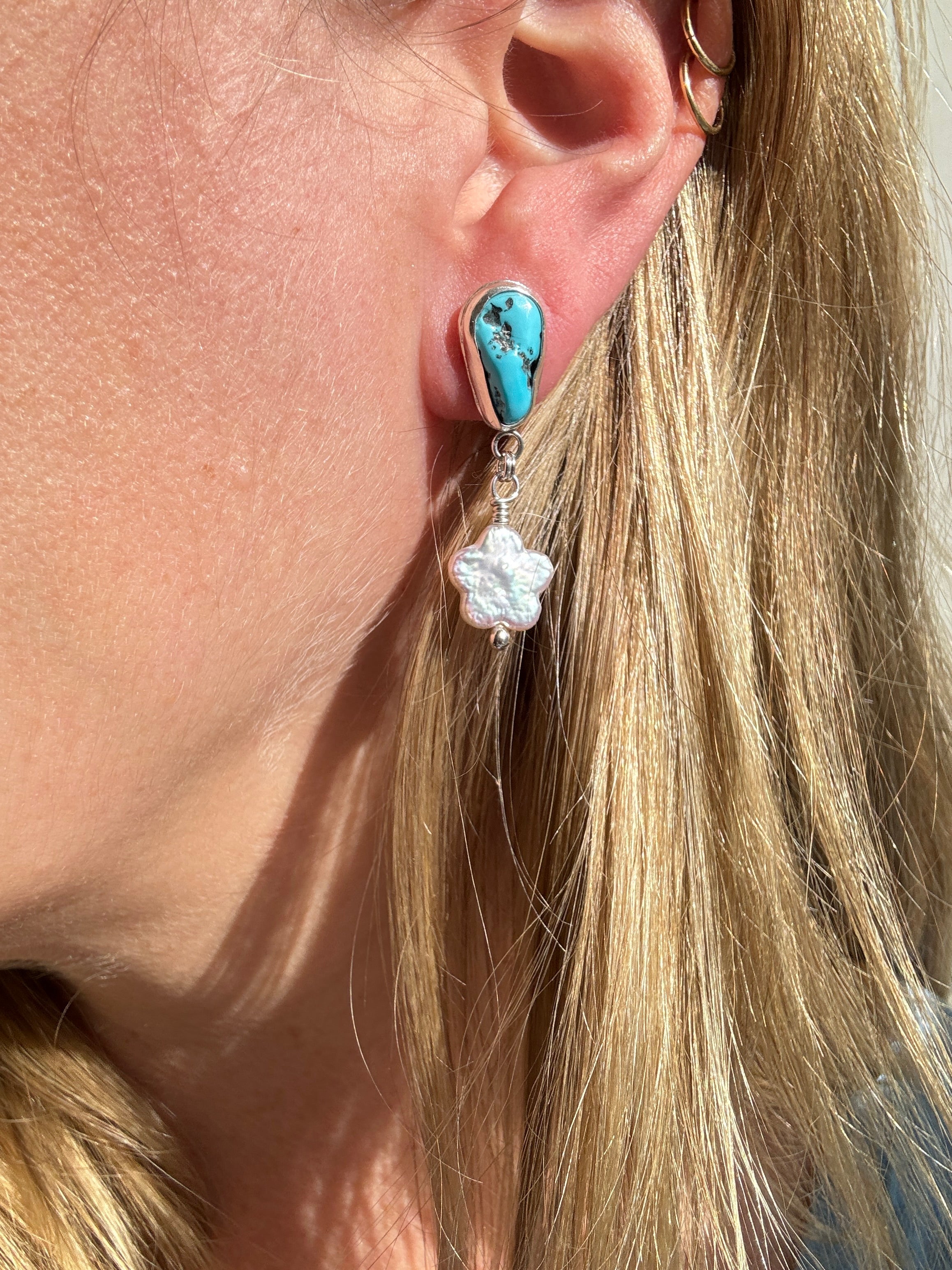 Castle Dome Turquoise set in a fine silver bezel with flower shaped pearls dangling below. The posts and ear backs are sterling silver.