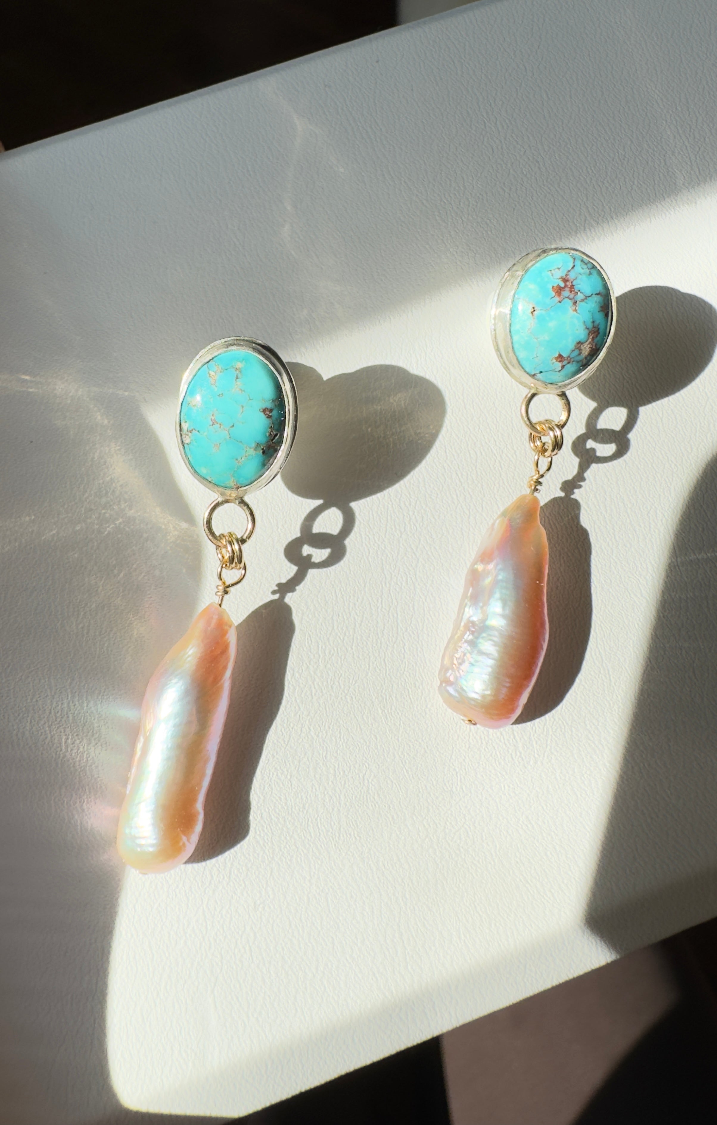 Egyptian Kingman Turquoise set in a fine silver bezel with pink pearls dangling below. The posts and ear backs are sterling silver.