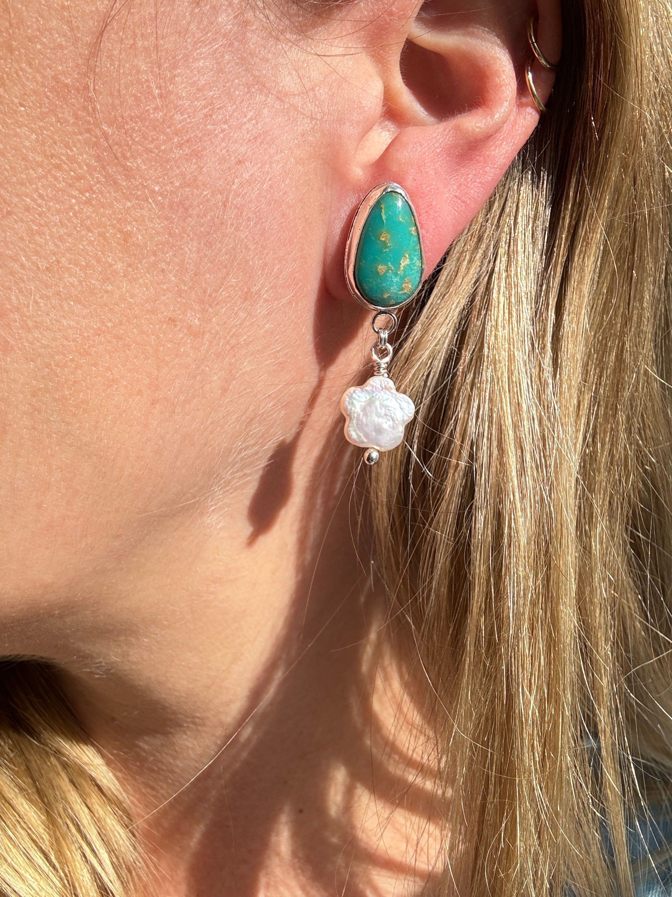 Royston Turquoise set in a fine silver bezel with flower shaped pearls dangling below. The posts and ear backs are sterling silver.