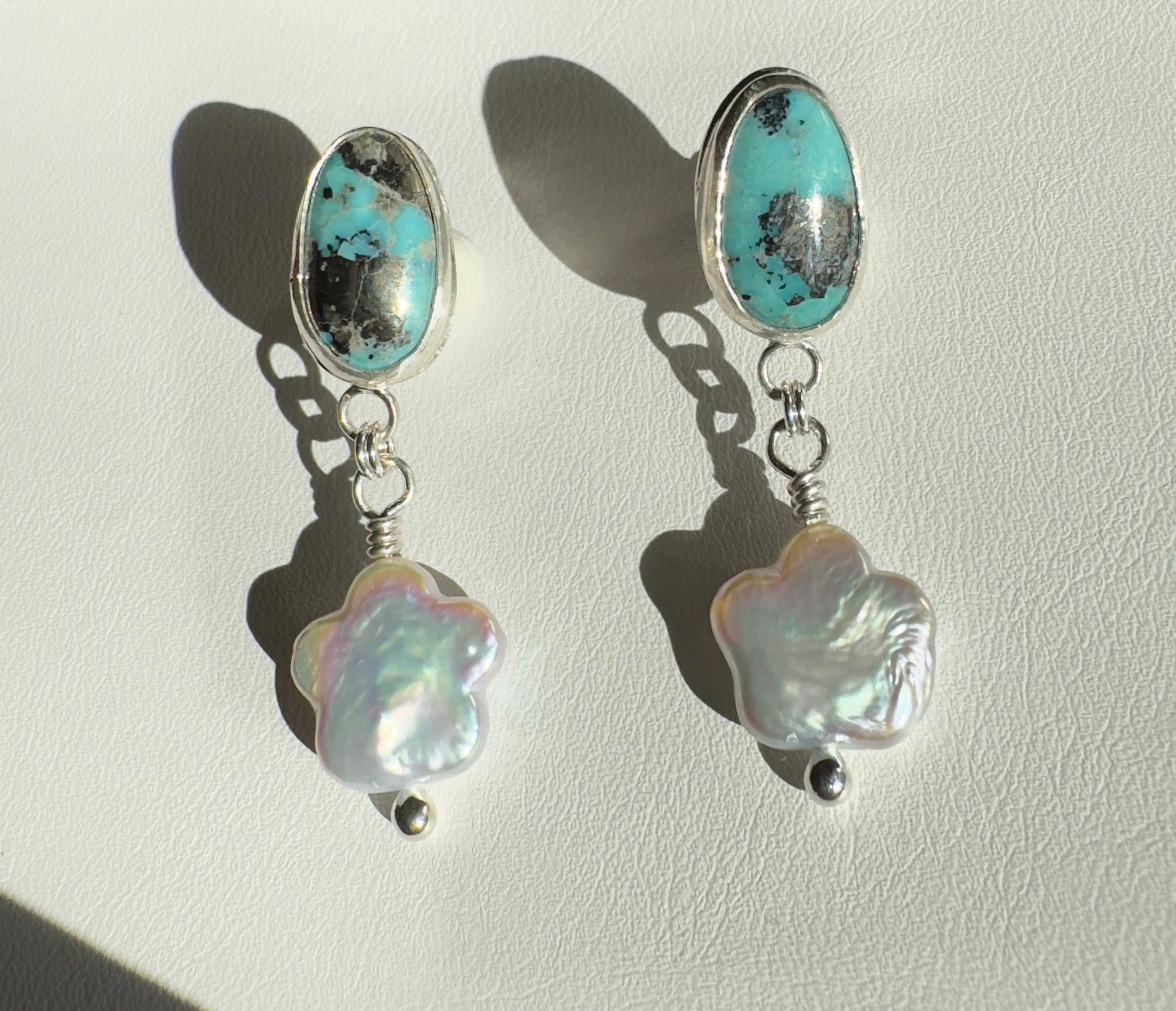 Robin's Egg Blue Kingman Turquoise set in a fine silver bezel with flower shaped pearls dangling below. The posts and ear backs are sterling silver.&nbsp;