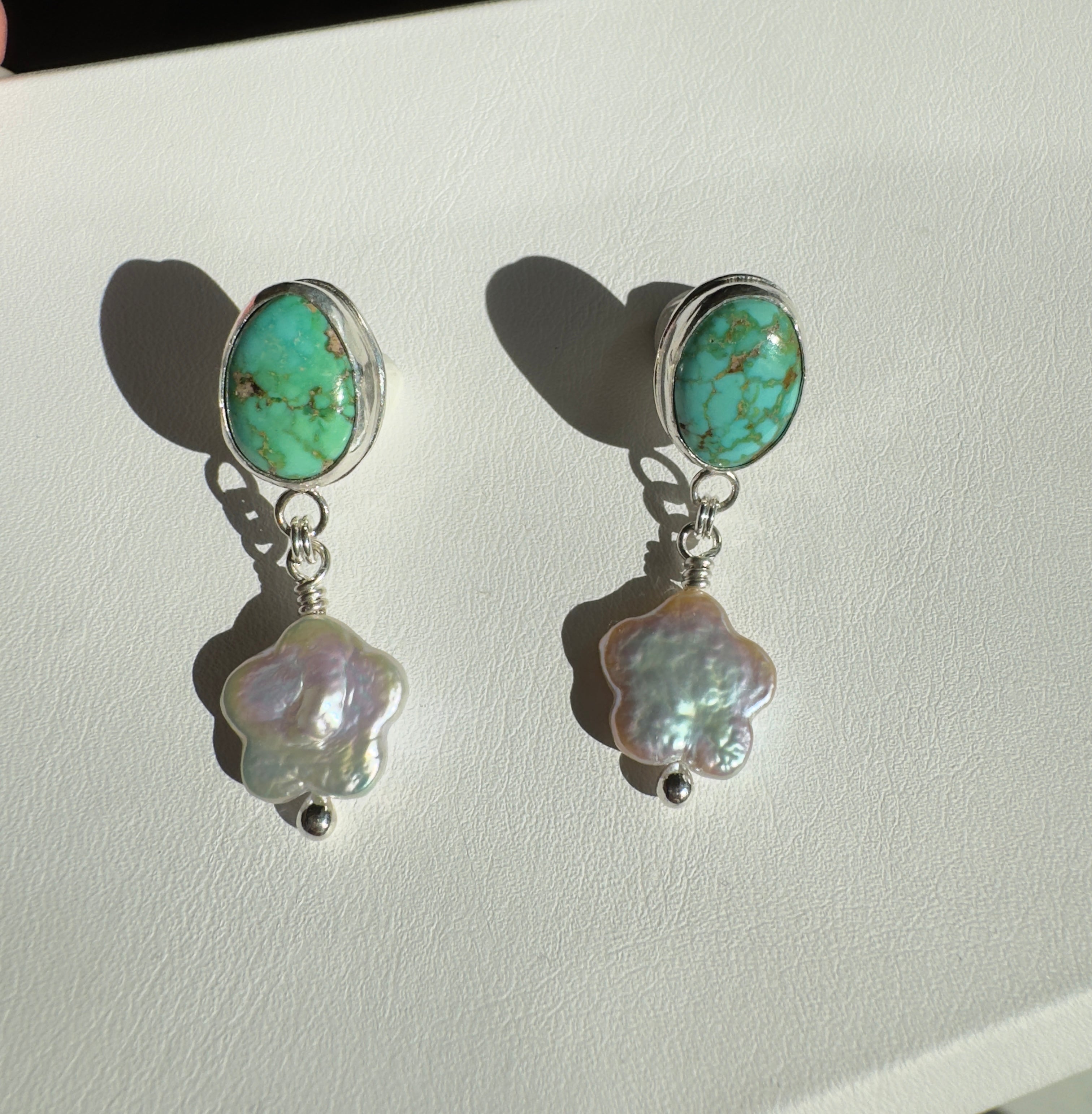 Verde Valley Turquoise set in a fine silver bezel with flower shaped pearls dangling below. The posts and ear backs are sterling silver.