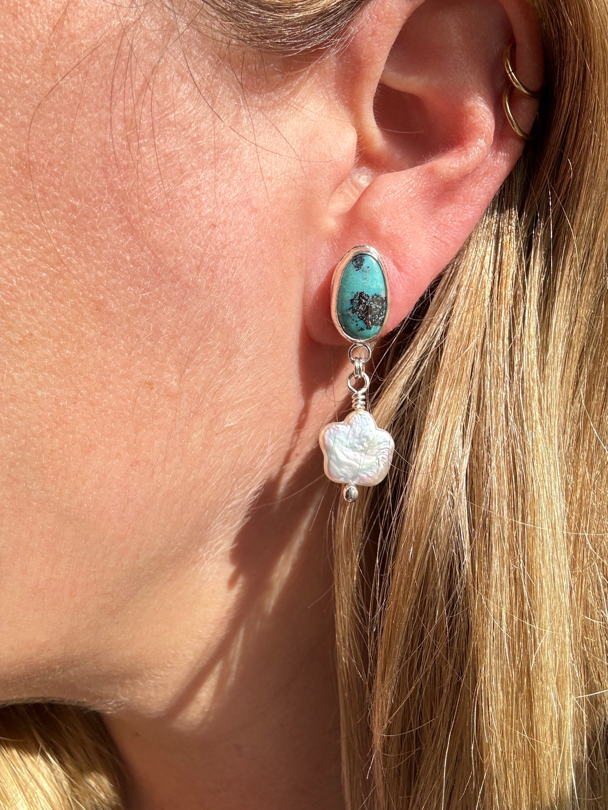 Robin's Egg Blue Kingman Turquoise set in a fine silver bezel with flower shaped pearls dangling below. The posts and ear backs are sterling silver.&nbsp;