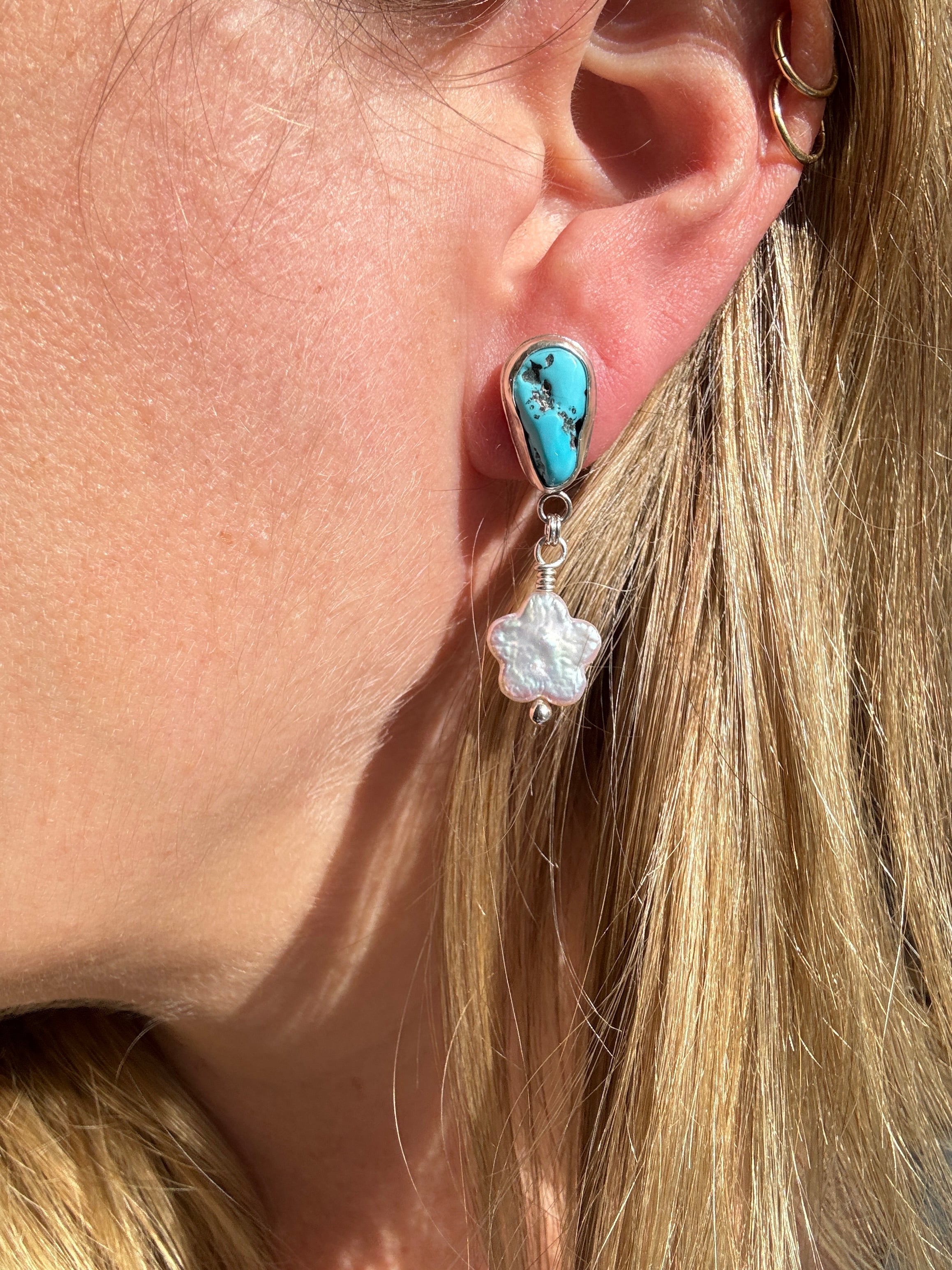 Castle Dome Turquoise set in a fine silver bezel with flower shaped pearls dangling below. The posts and ear backs are sterling silver.