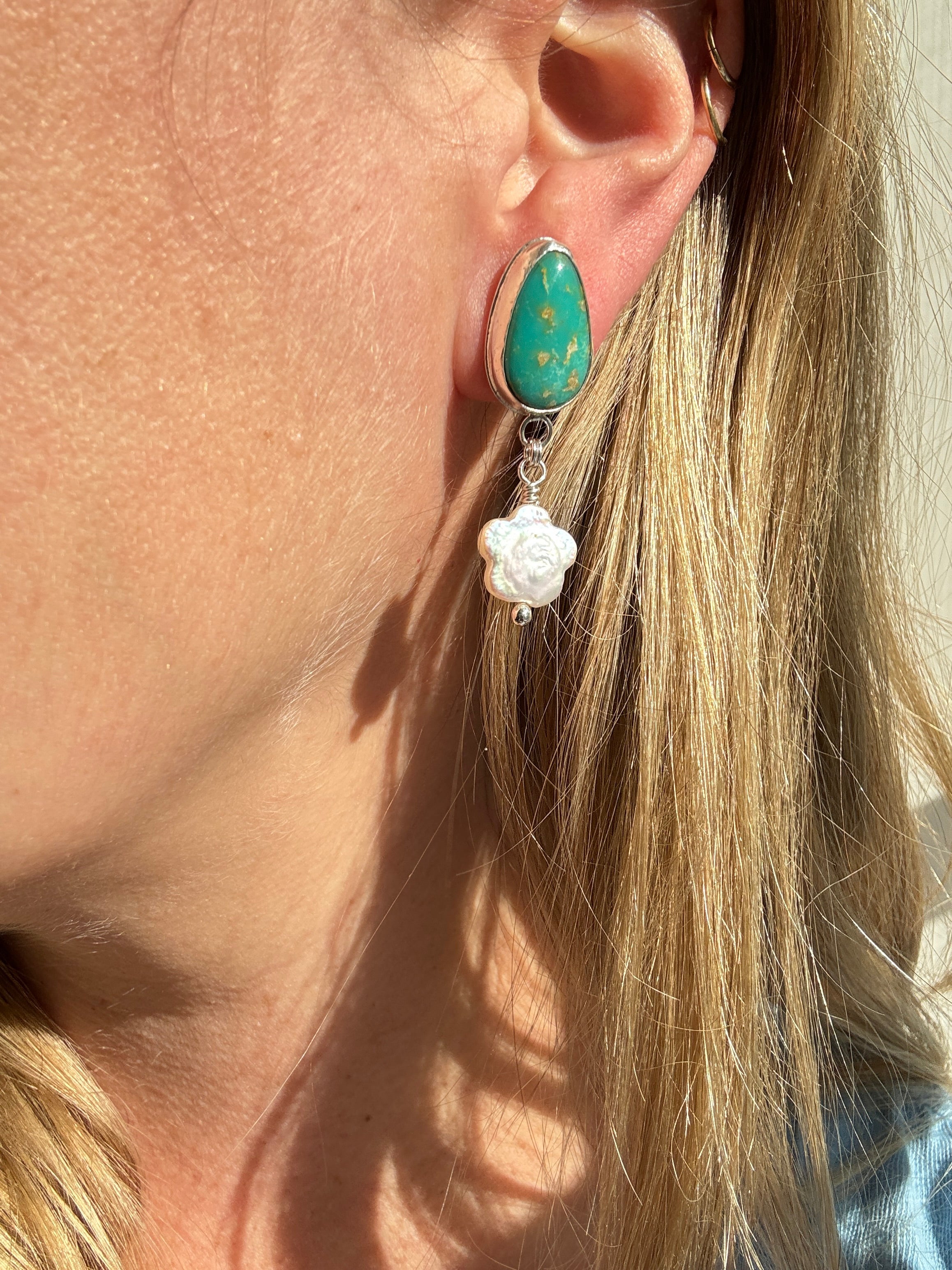 Royston Turquoise set in a fine silver bezel with flower shaped pearls dangling below. The posts and ear backs are sterling silver.