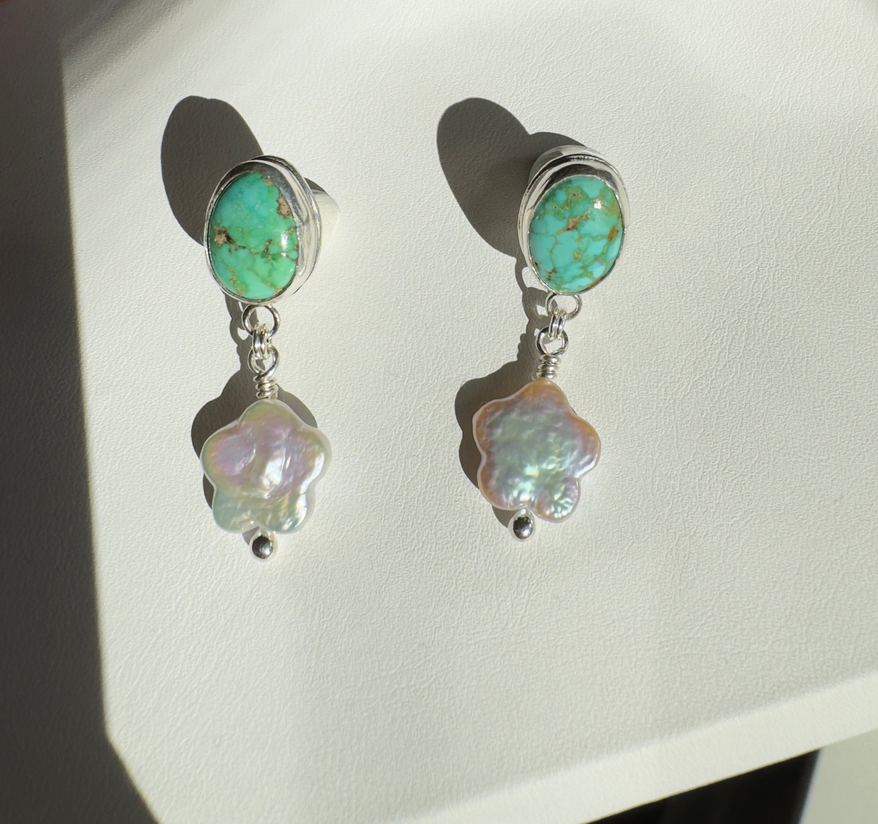 Verde Valley Turquoise set in a fine silver bezel with flower shaped pearls dangling below. The posts and ear backs are sterling silver.