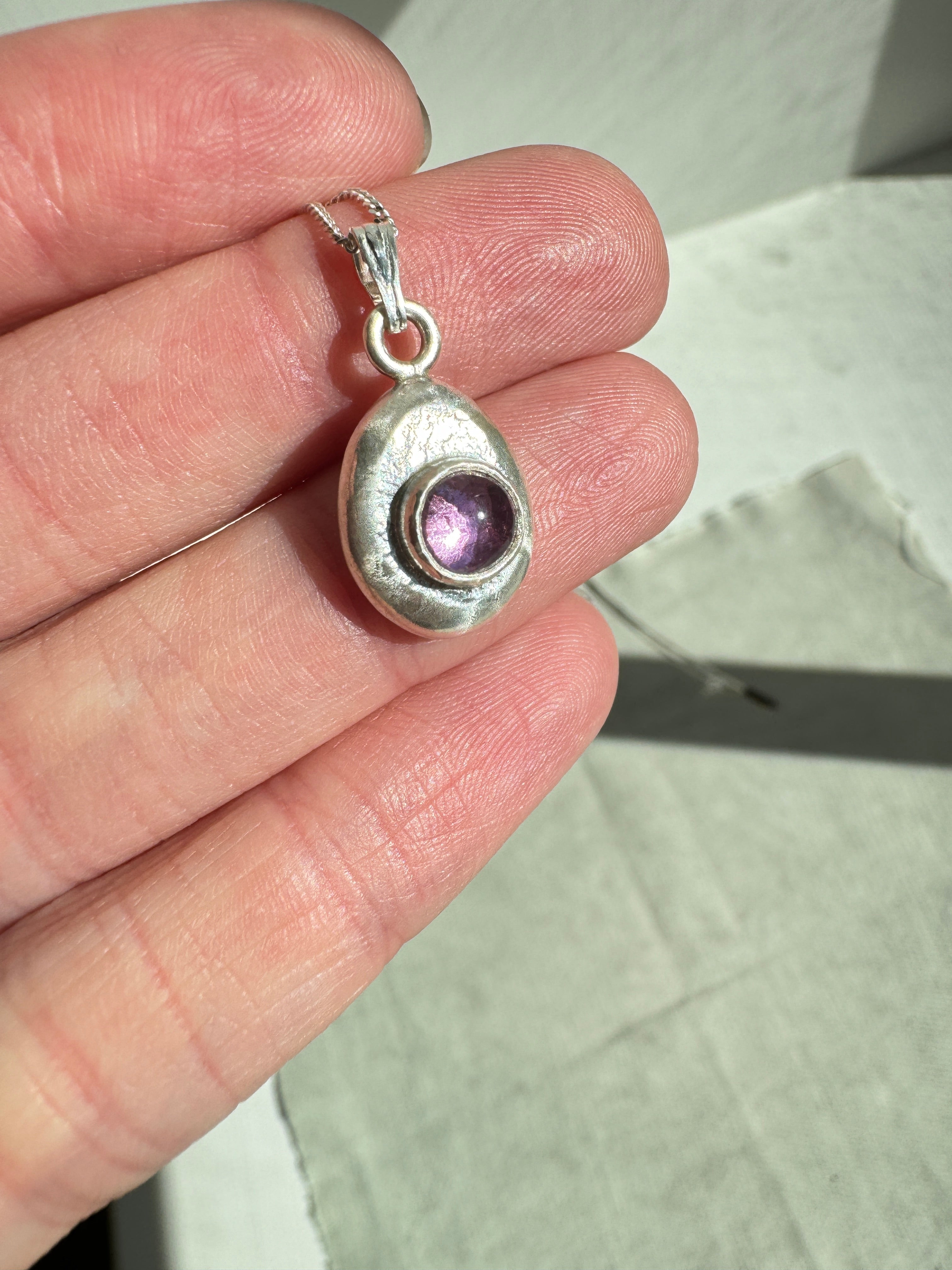 6mm Pink Sapphire (lab created) on a hand forged nugget of sterling silver. Choose between a 16” or 18” sterling silver diamond cut curb chain.