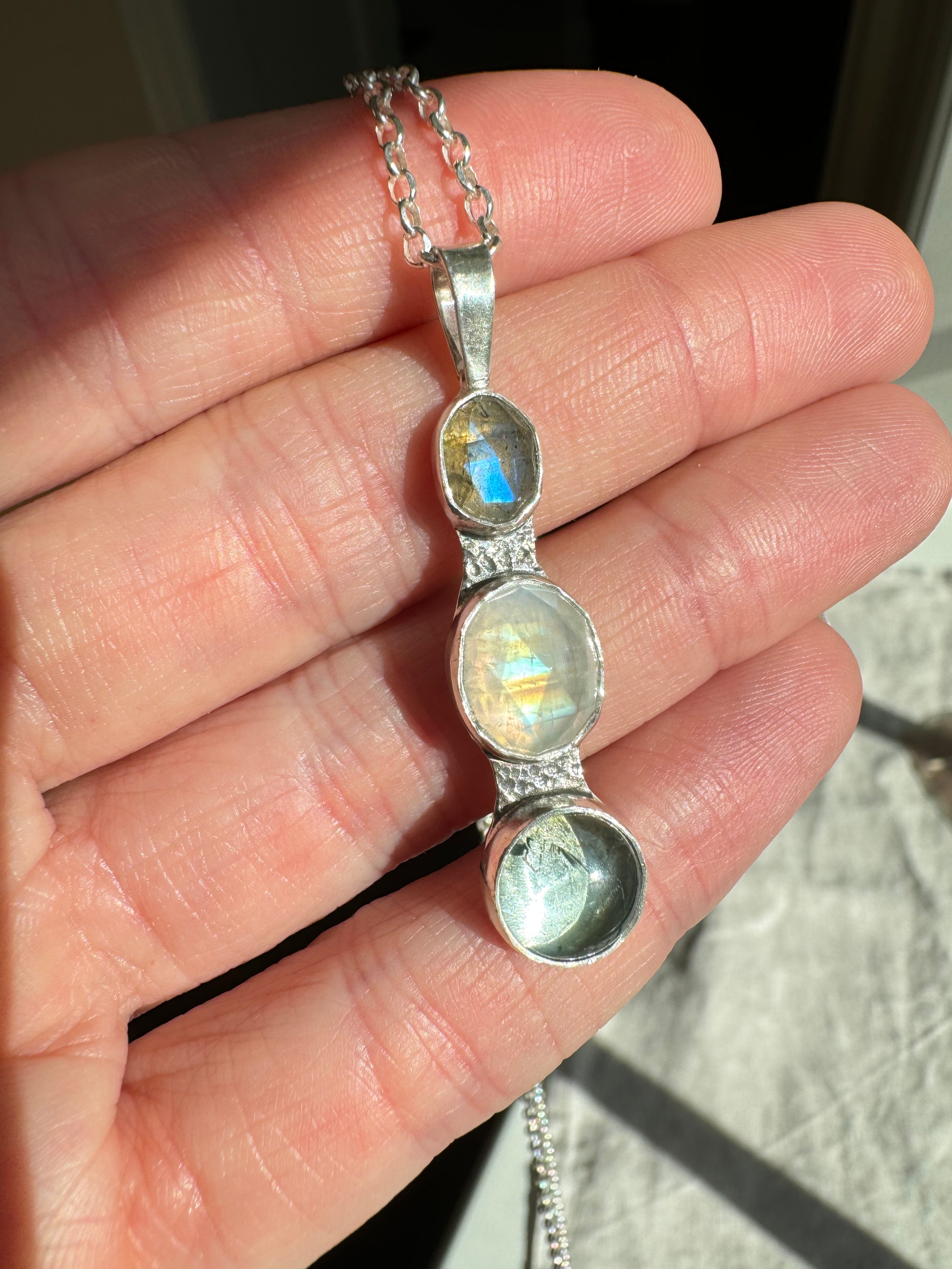 Icy blues of labradorite, moonstone and aquamarine set in fine silver bezels on a sterling silver back. This one of a kind pendant hangs from an 18" 2mm diamond cut Figaro chain.