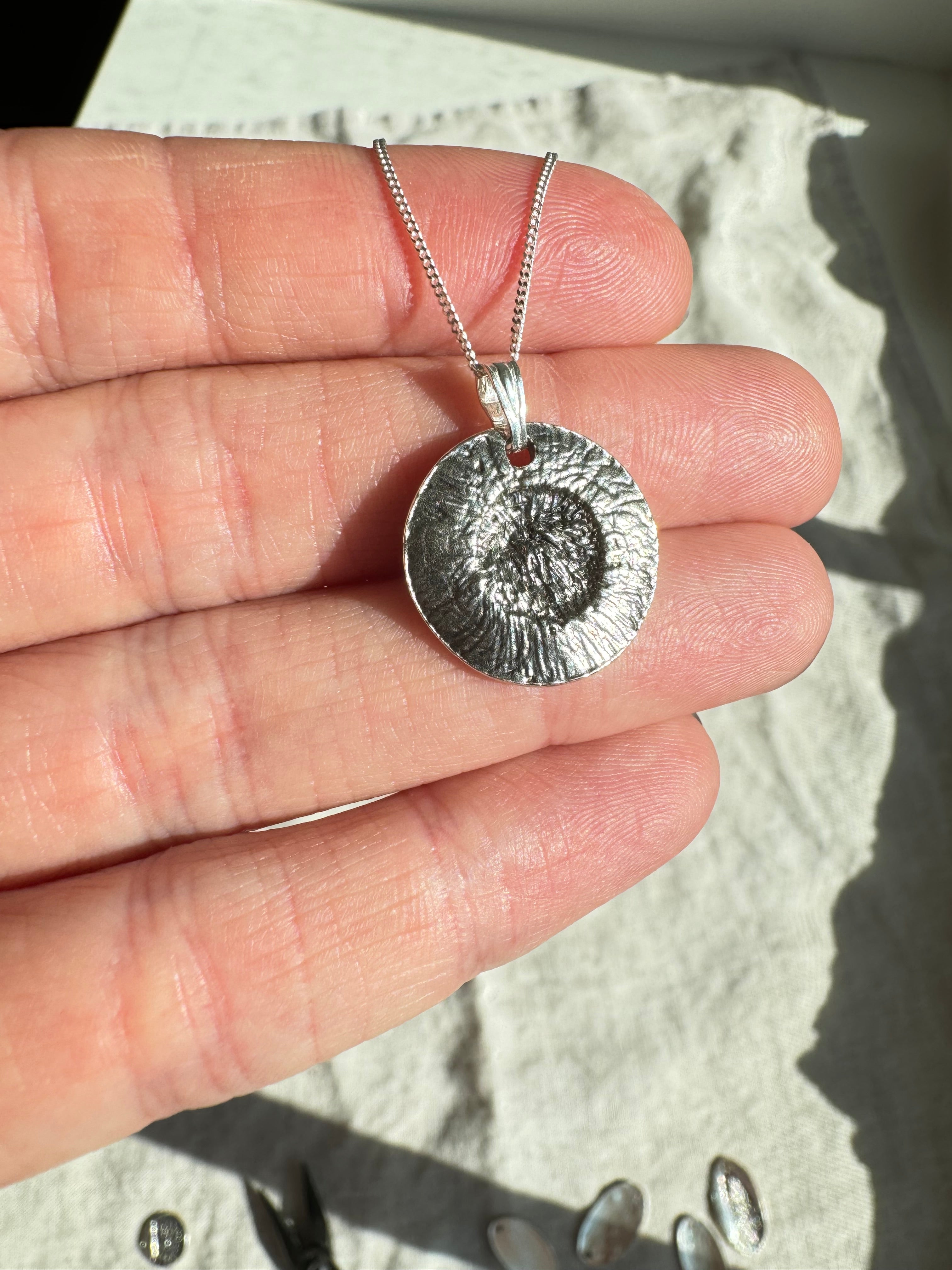 Hand pressed aster on fine silver with a sterling silver bail. Choose between a 16” or 18” sterling silver diamond cut curb chain.