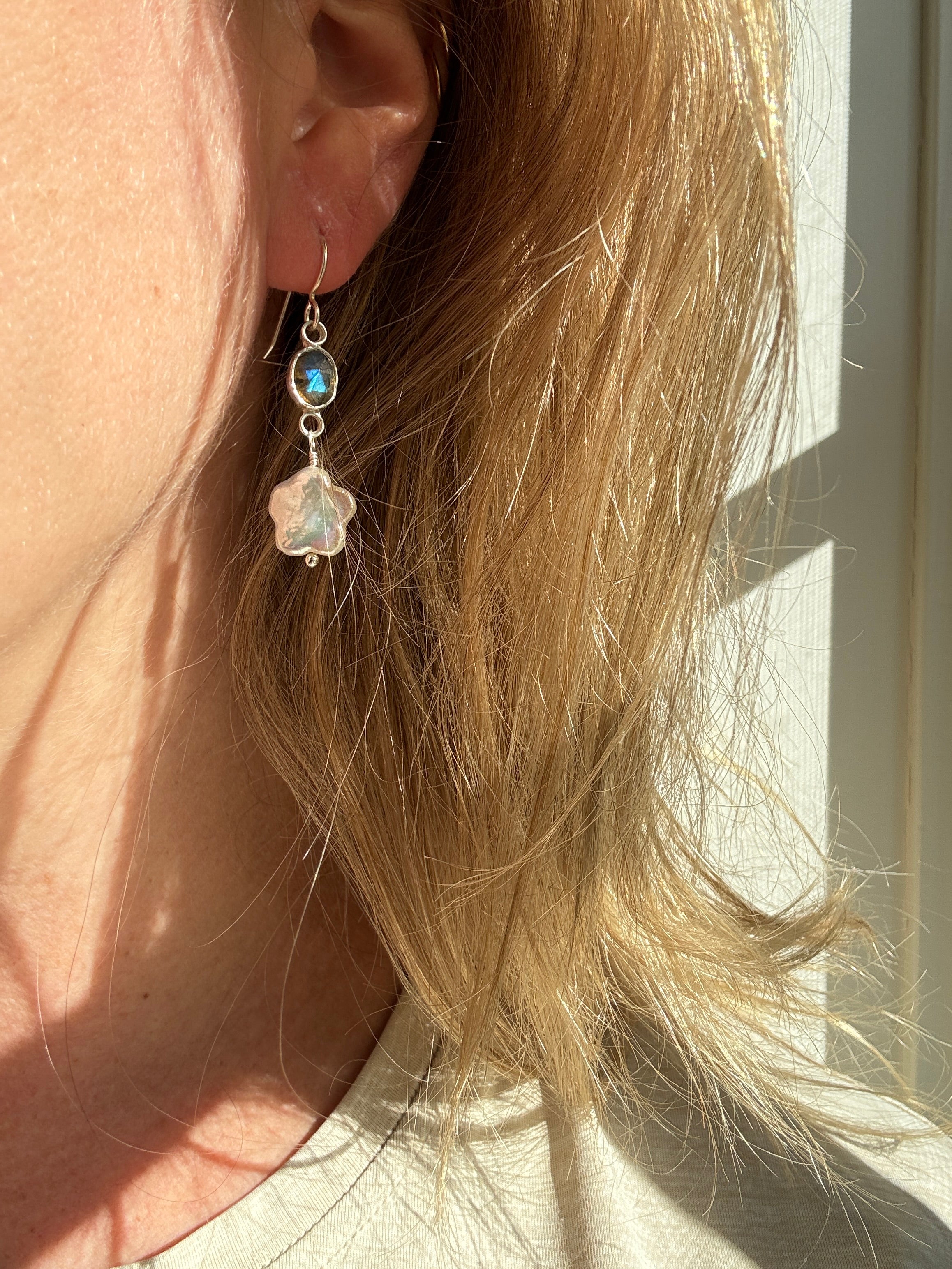 Icy blue labradorite set in a fine silver bezel on a sterling silver back with freshwater flower-shaped pearls dangling below.