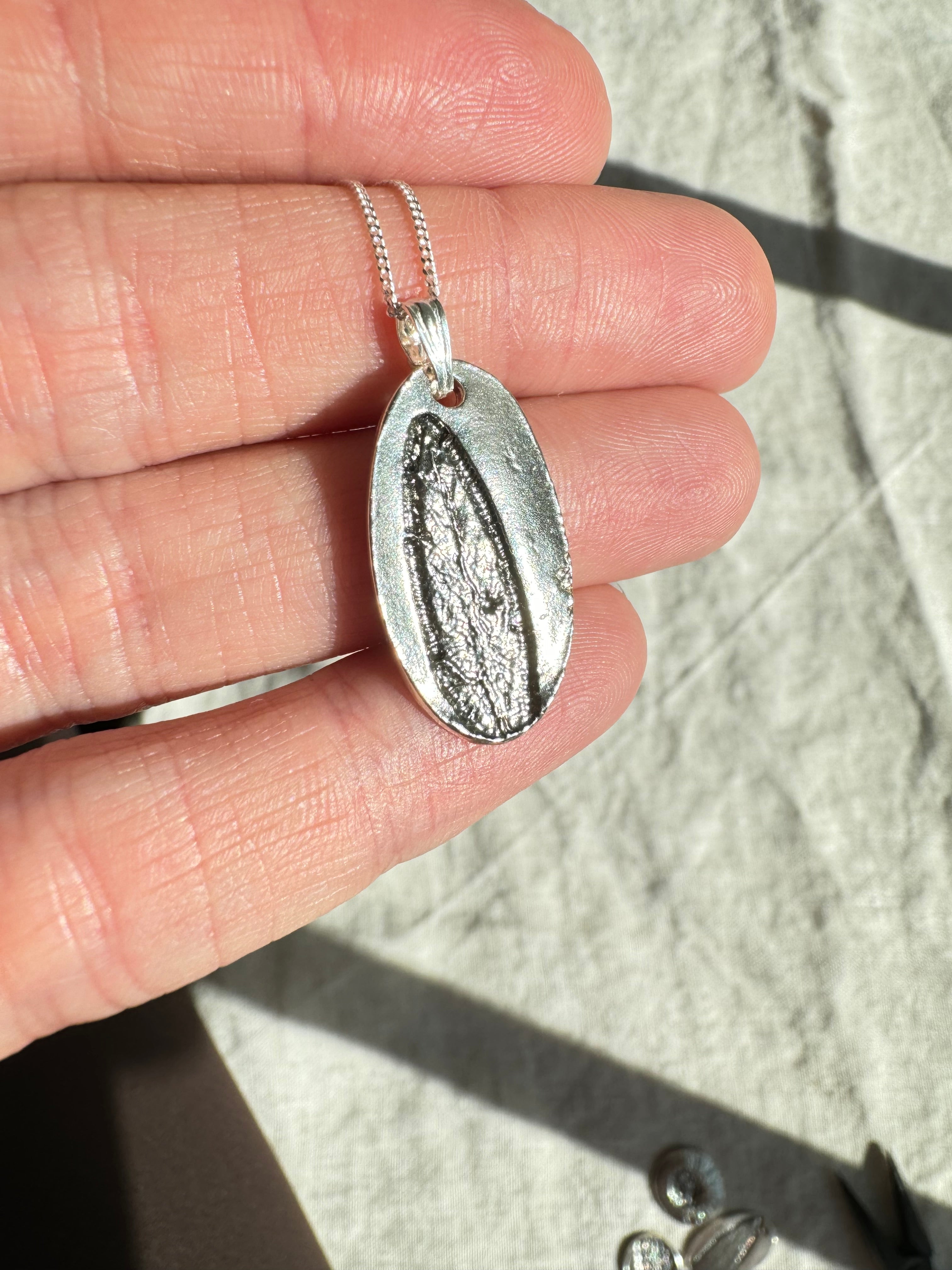 Hand pressed sage on fine silver with a sterling silver bail. Choose between a 16” or 18” sterling silver diamond cut curb chain.