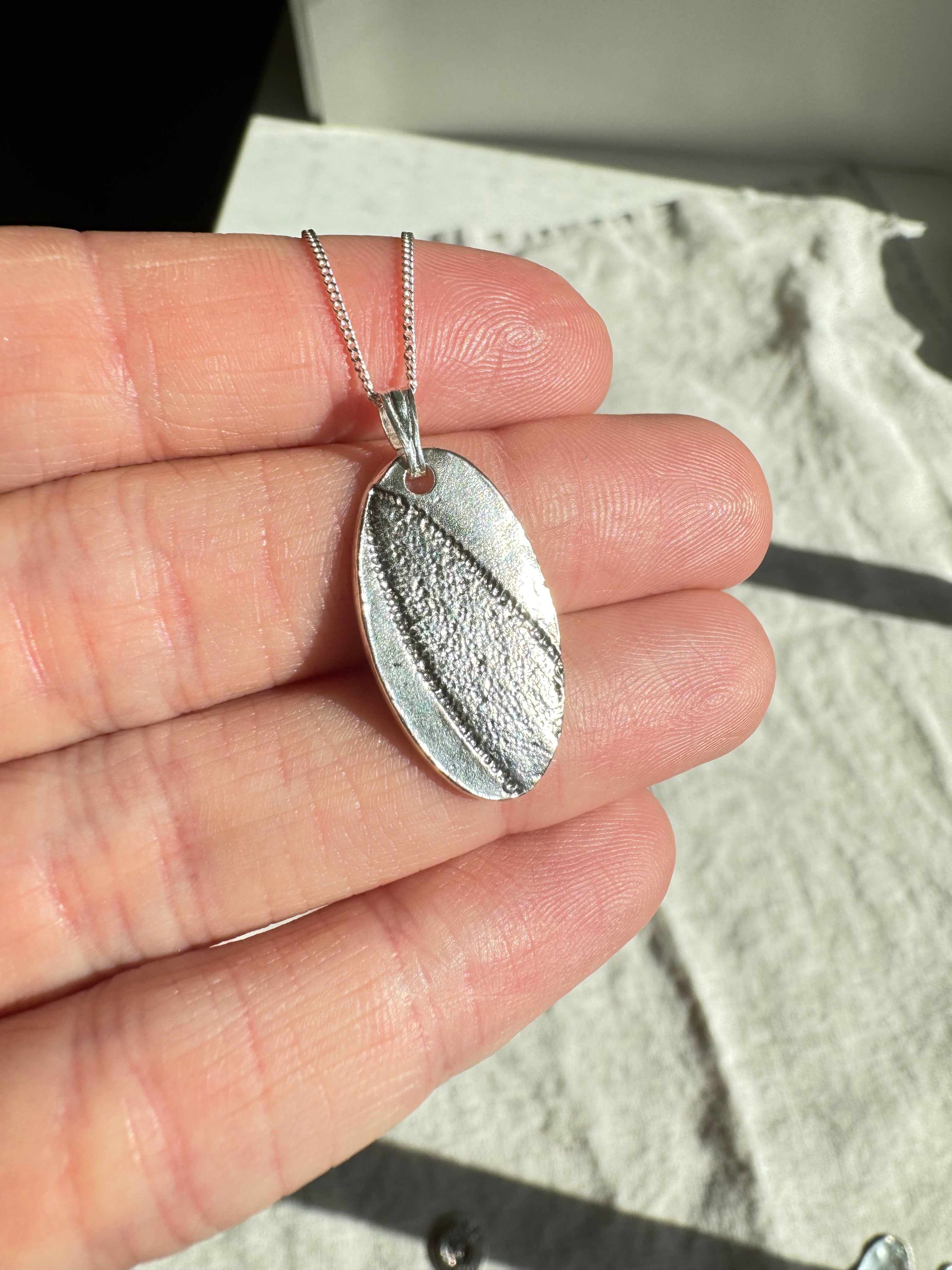 Hand pressed sage on fine silver with a sterling silver bail. Choose between a 16” or 18” sterling silver diamond cut curb chain.