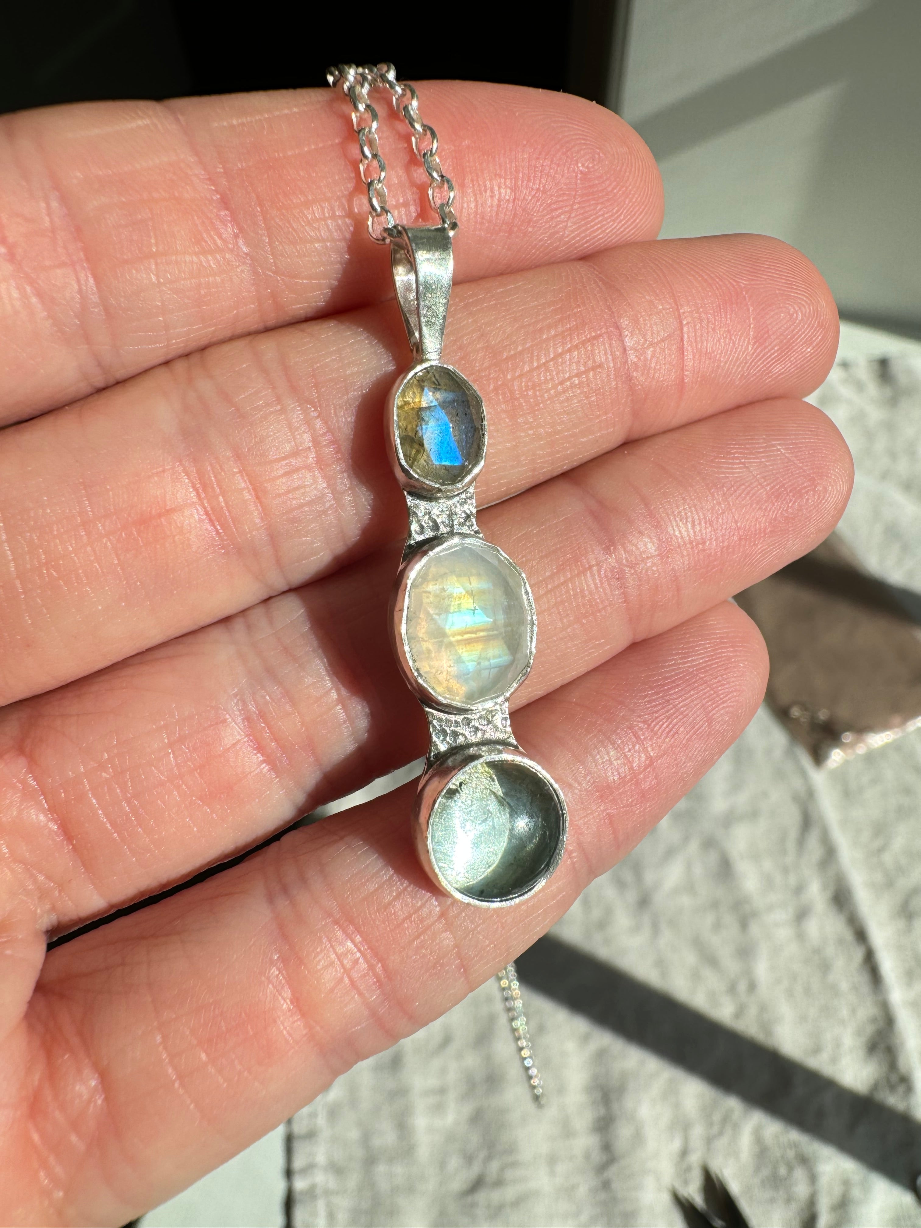 Icy blues of labradorite, moonstone and aquamarine set in fine silver bezels on a sterling silver back. This one of a kind pendant hangs from an 18" 2mm diamond cut Figaro chain.