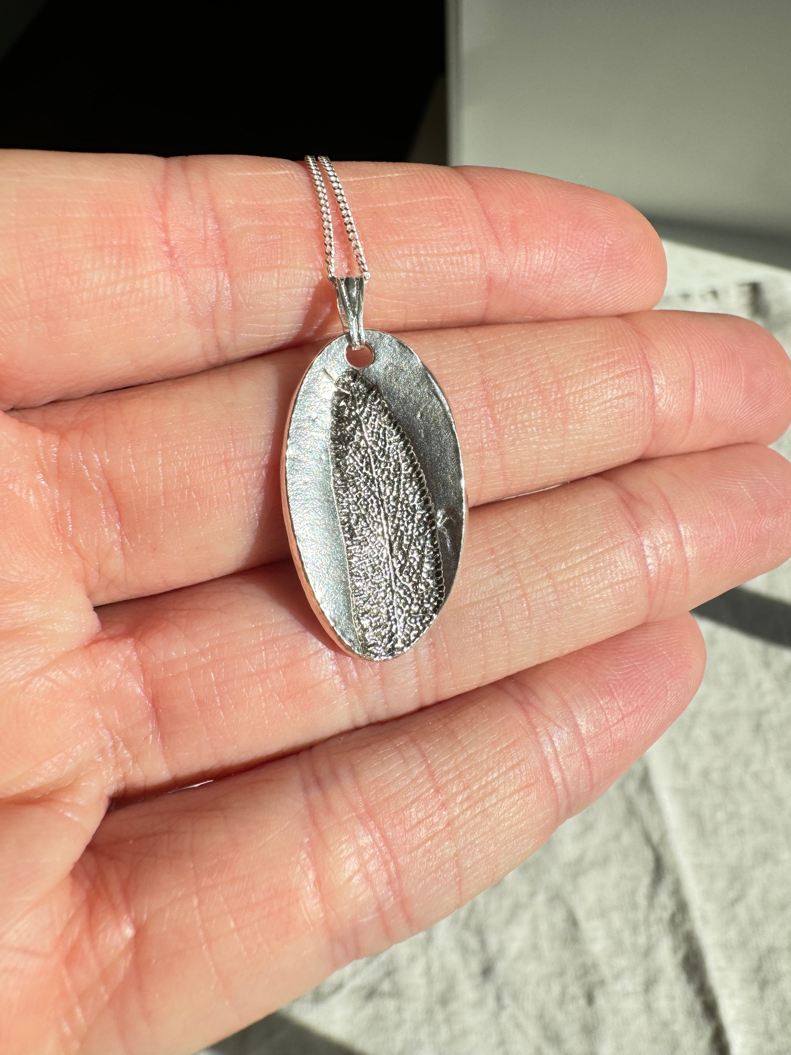 Hand pressed sage on fine silver with a sterling silver chain.