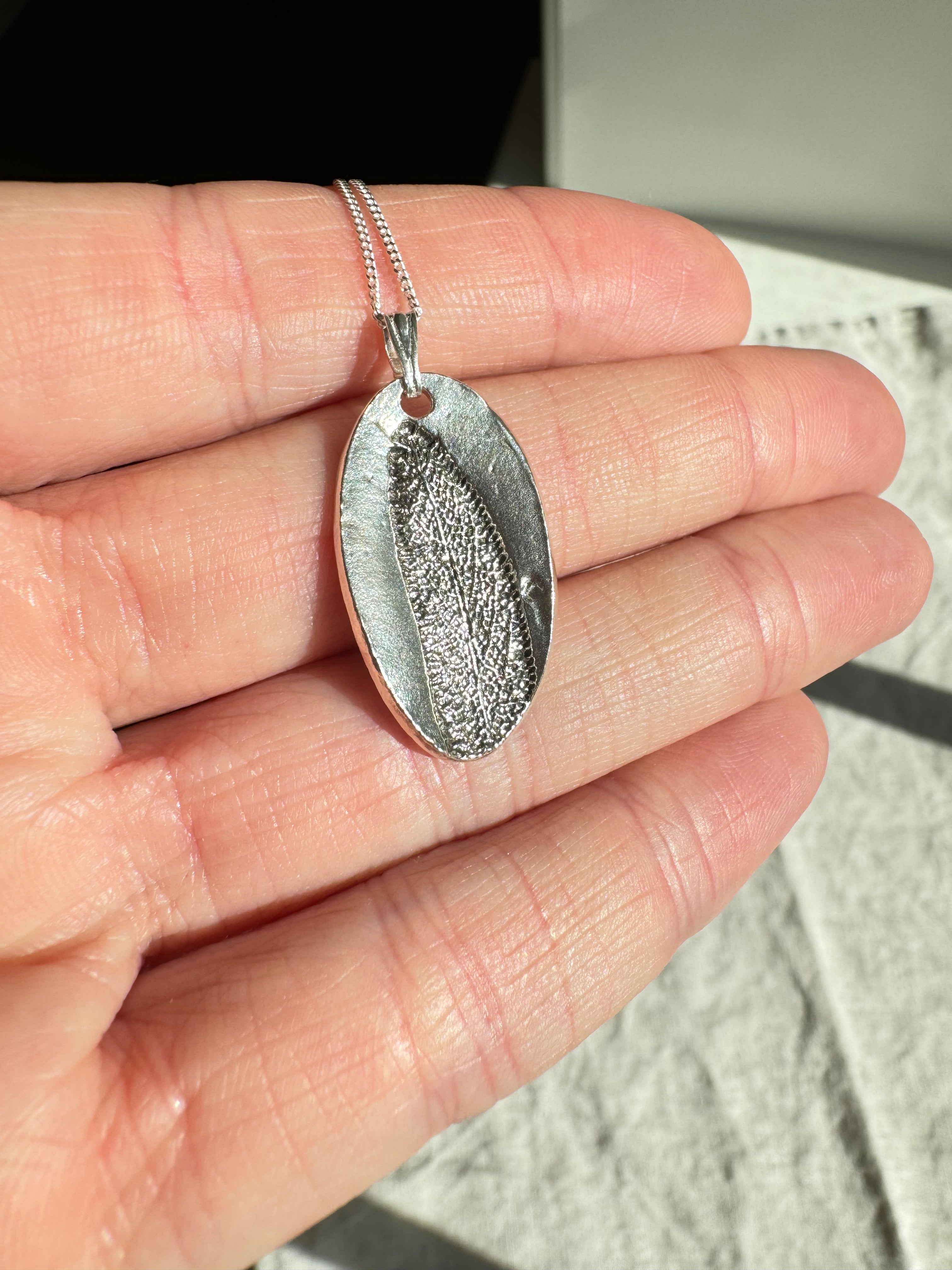 Hand pressed sage on fine silver with a sterling silver chain.