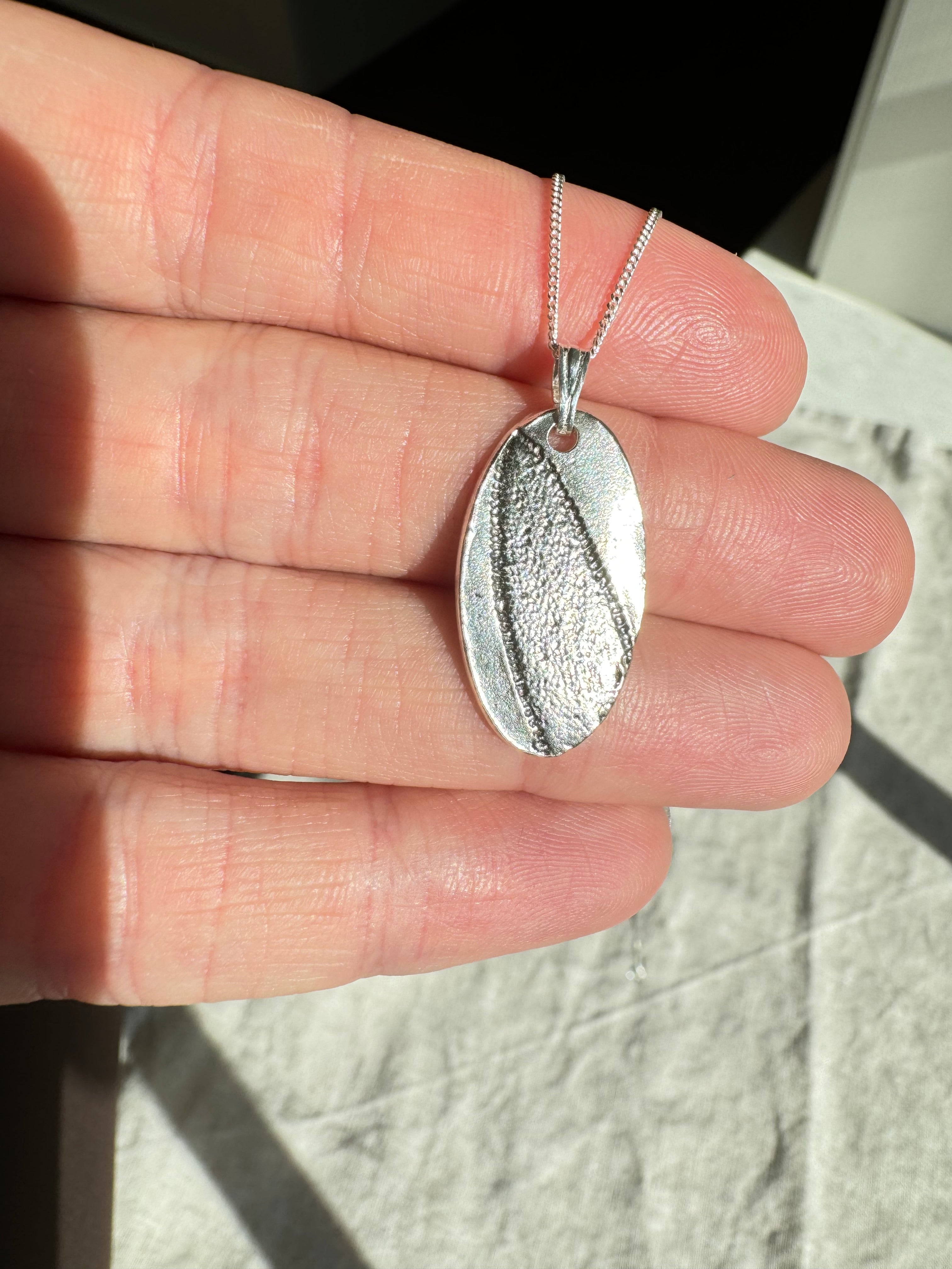 Hand pressed sage on fine silver with a sterling silver bail. Choose between a 16” or 18” sterling silver diamond cut curb chain.