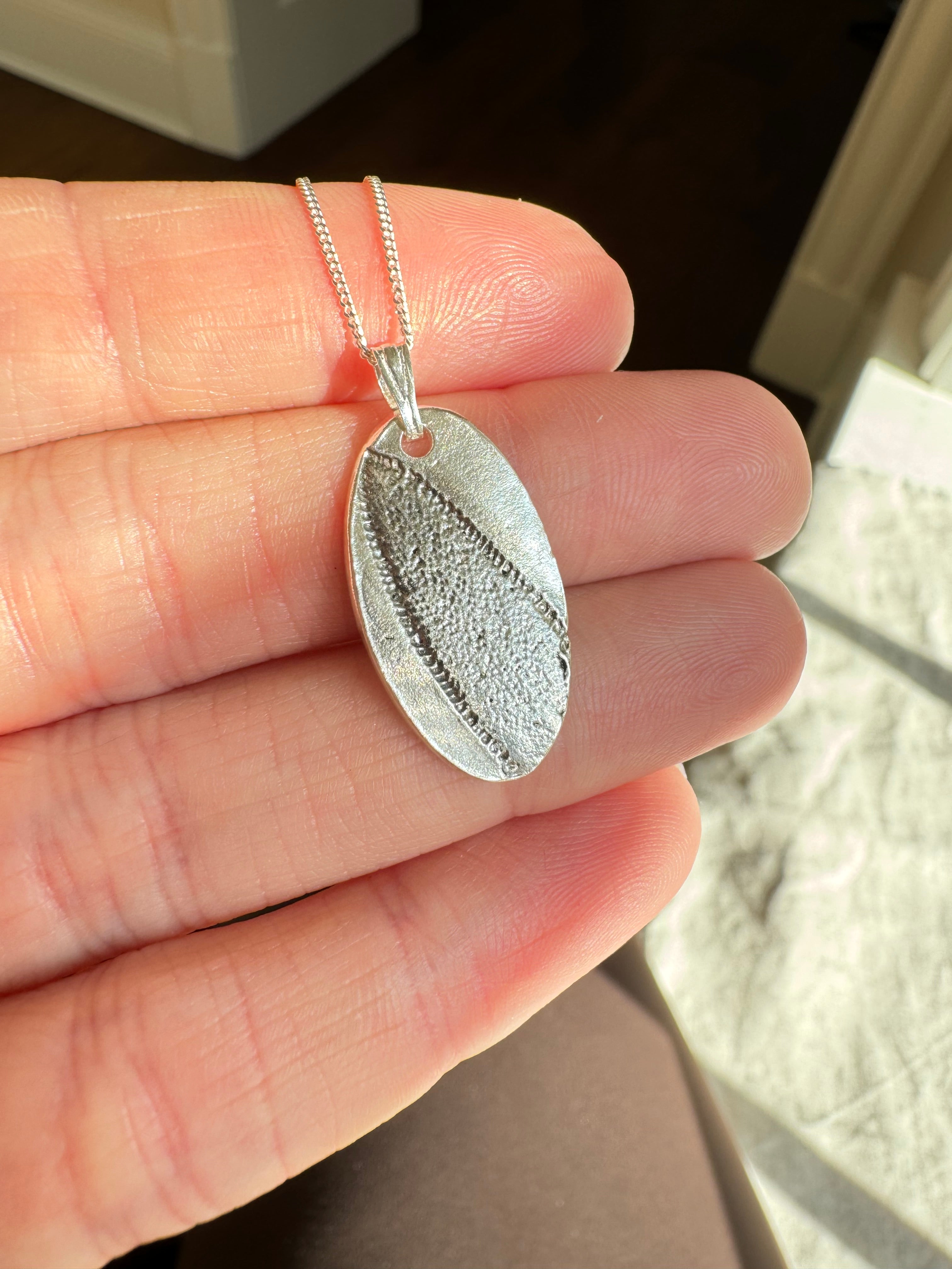 Hand pressed sage on fine silver with a sterling silver bail. Choose between a 16” or 18” sterling silver diamond cut curb chain.