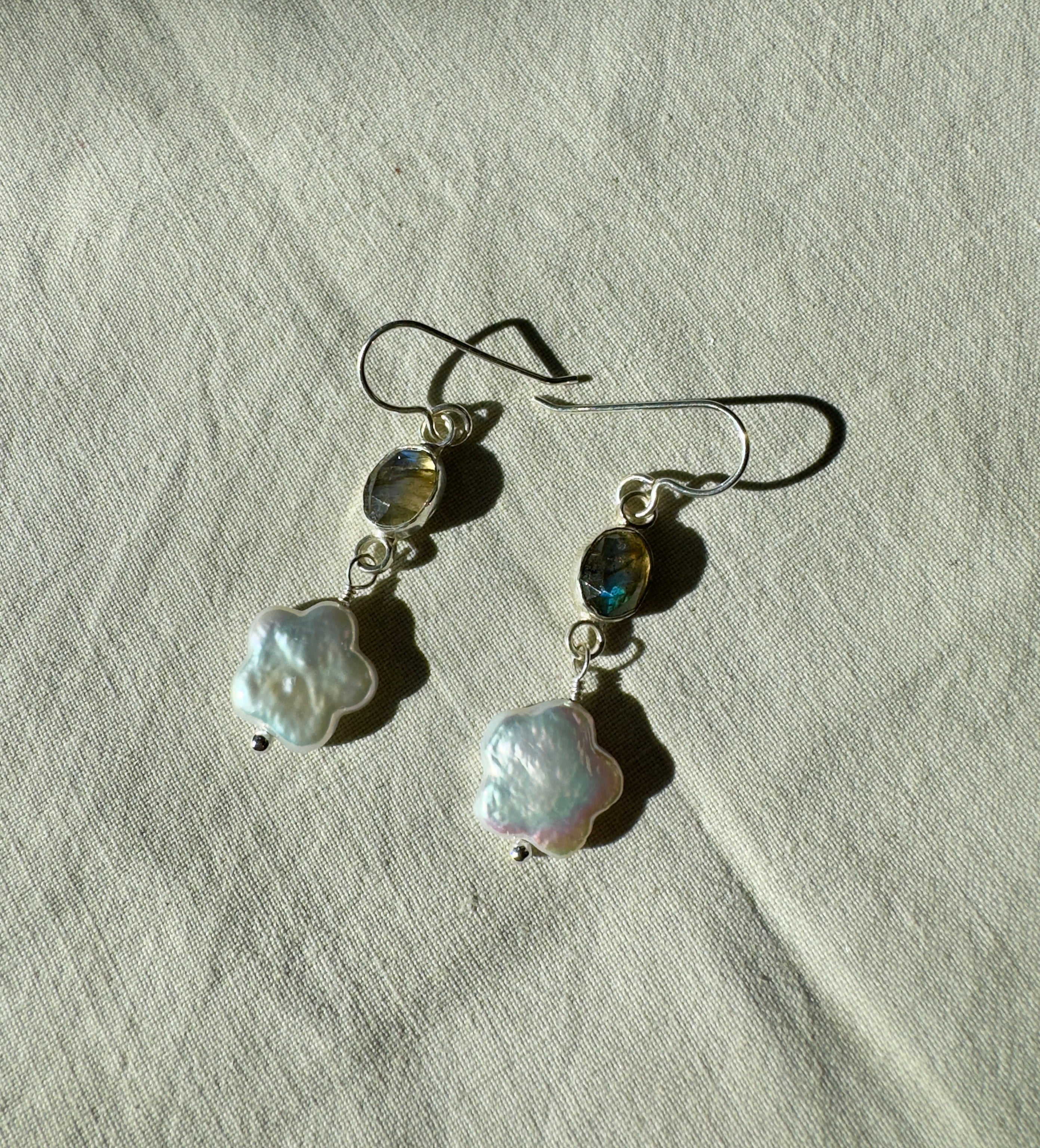 Icy blue labradorite set in a fine silver bezel on a sterling silver back with freshwater flower-shaped pearls dangling below.